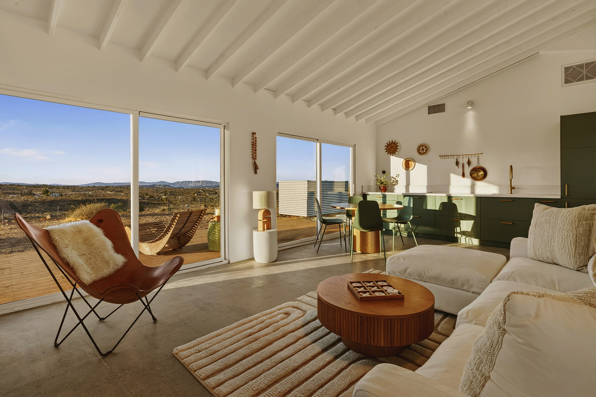 Casita living room with butterfly chair, kitchen with green cabinets and desert view