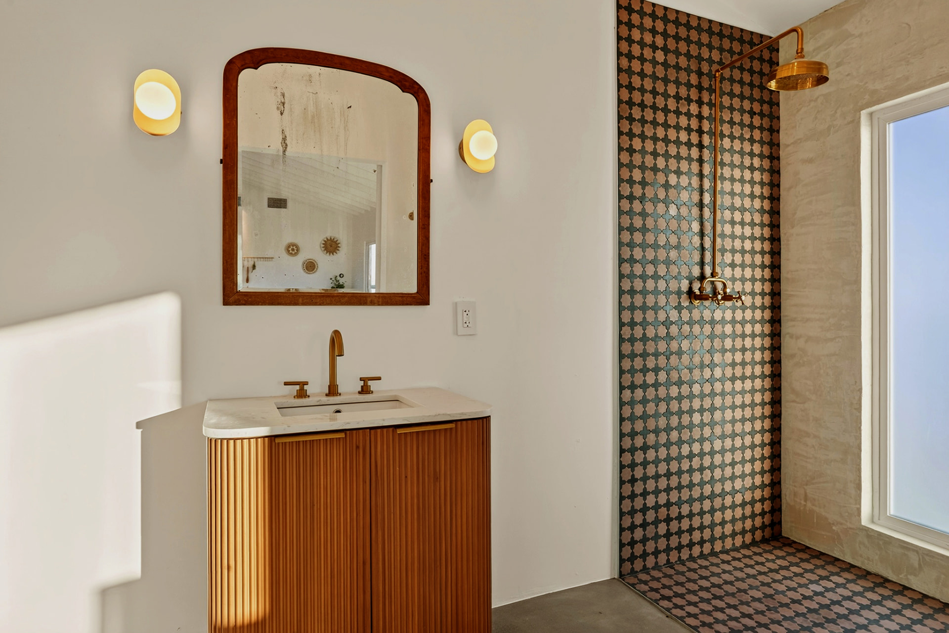 Casita bathroom with wood vanity, brass fixtures and patterned tile shower
