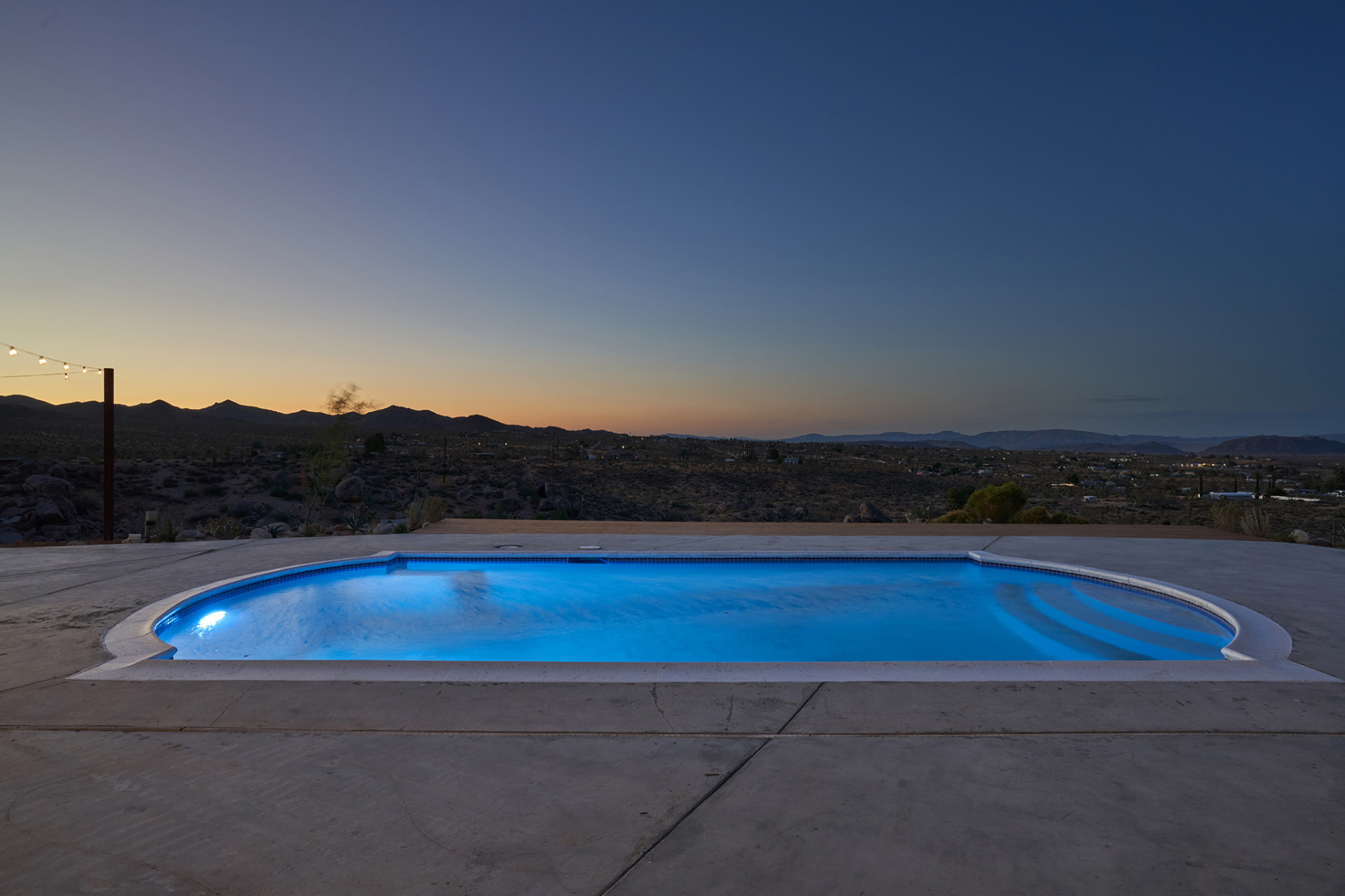 Illuminated pool at dusk overlooking the valley and mountains