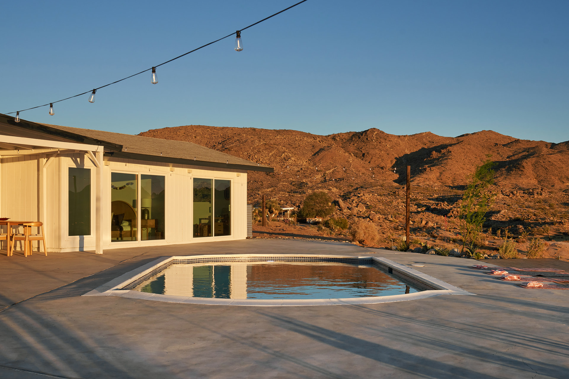 Pool with mountain backdrop, string lights and stepping stones