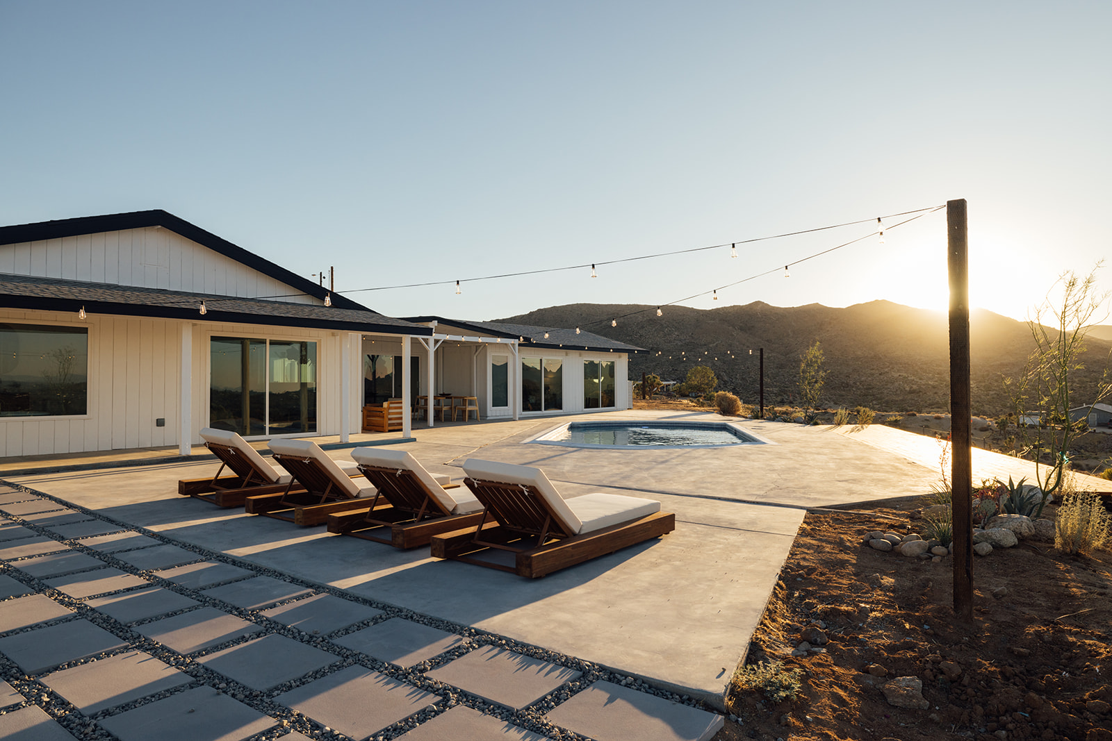 Pool deck with chaise loungers and string lights at golden hour