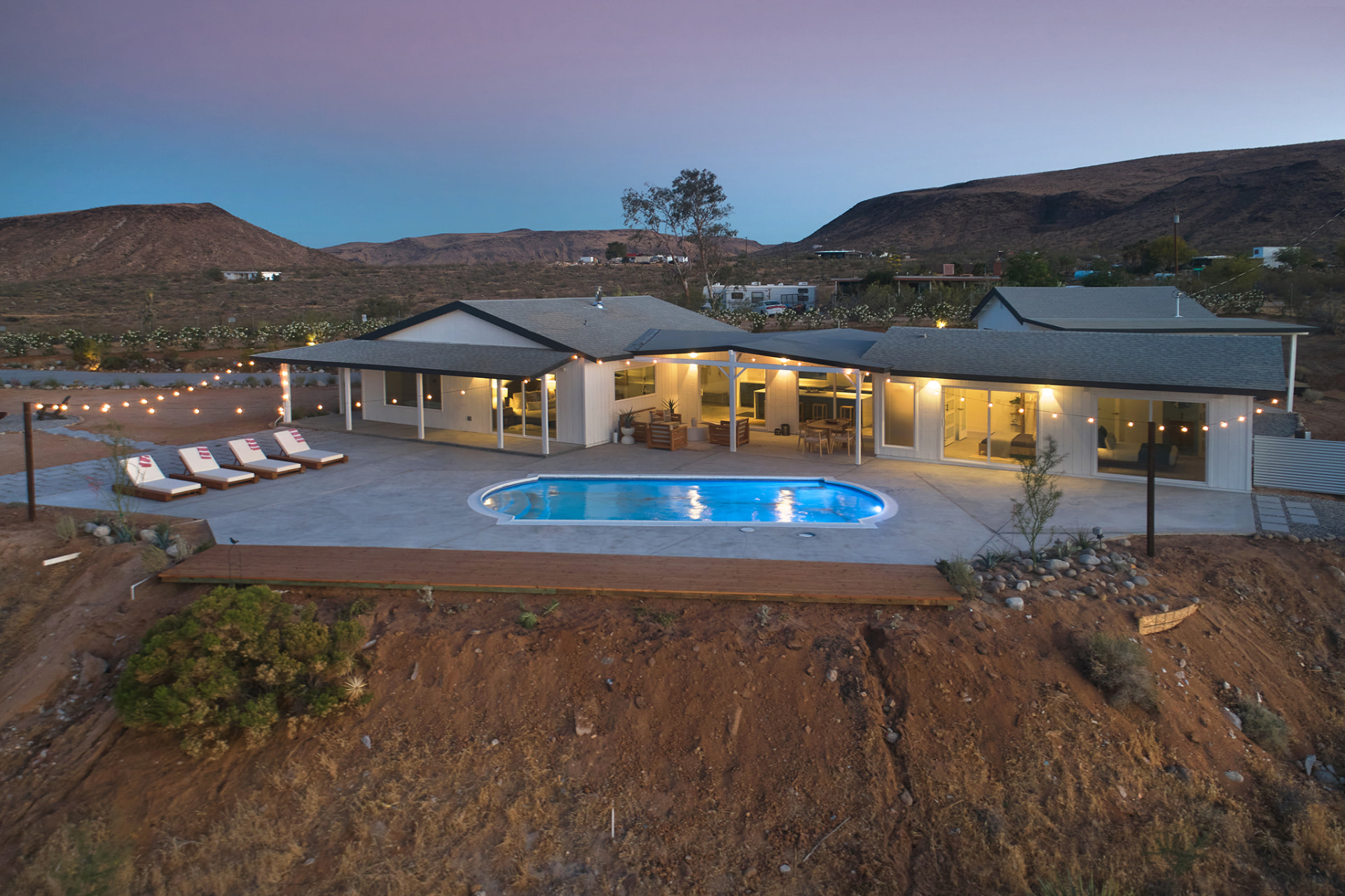 Aerial view of the estate and lit pool at blue hour