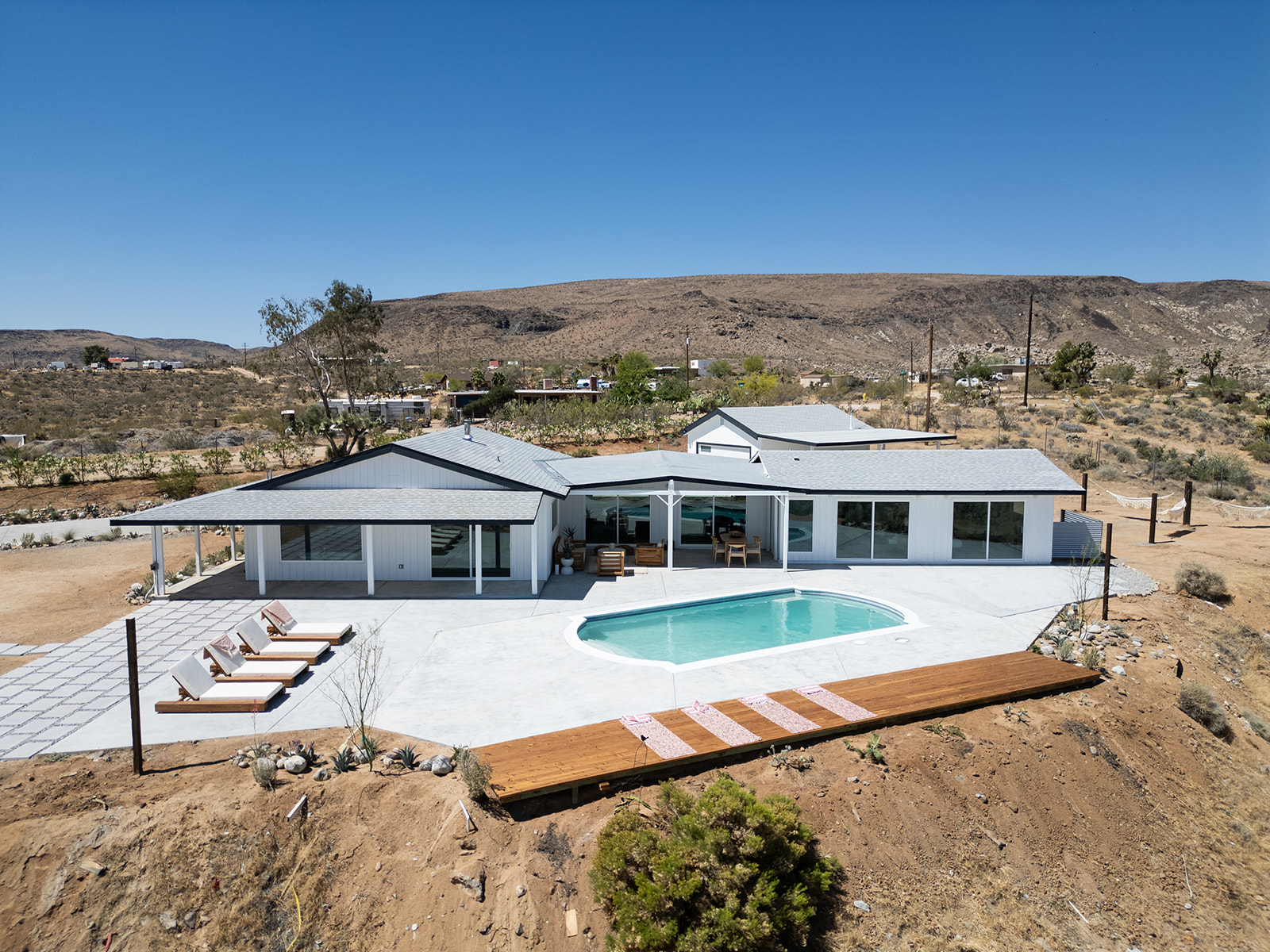 Aerial daytime view of the house, pool and casita against the hills