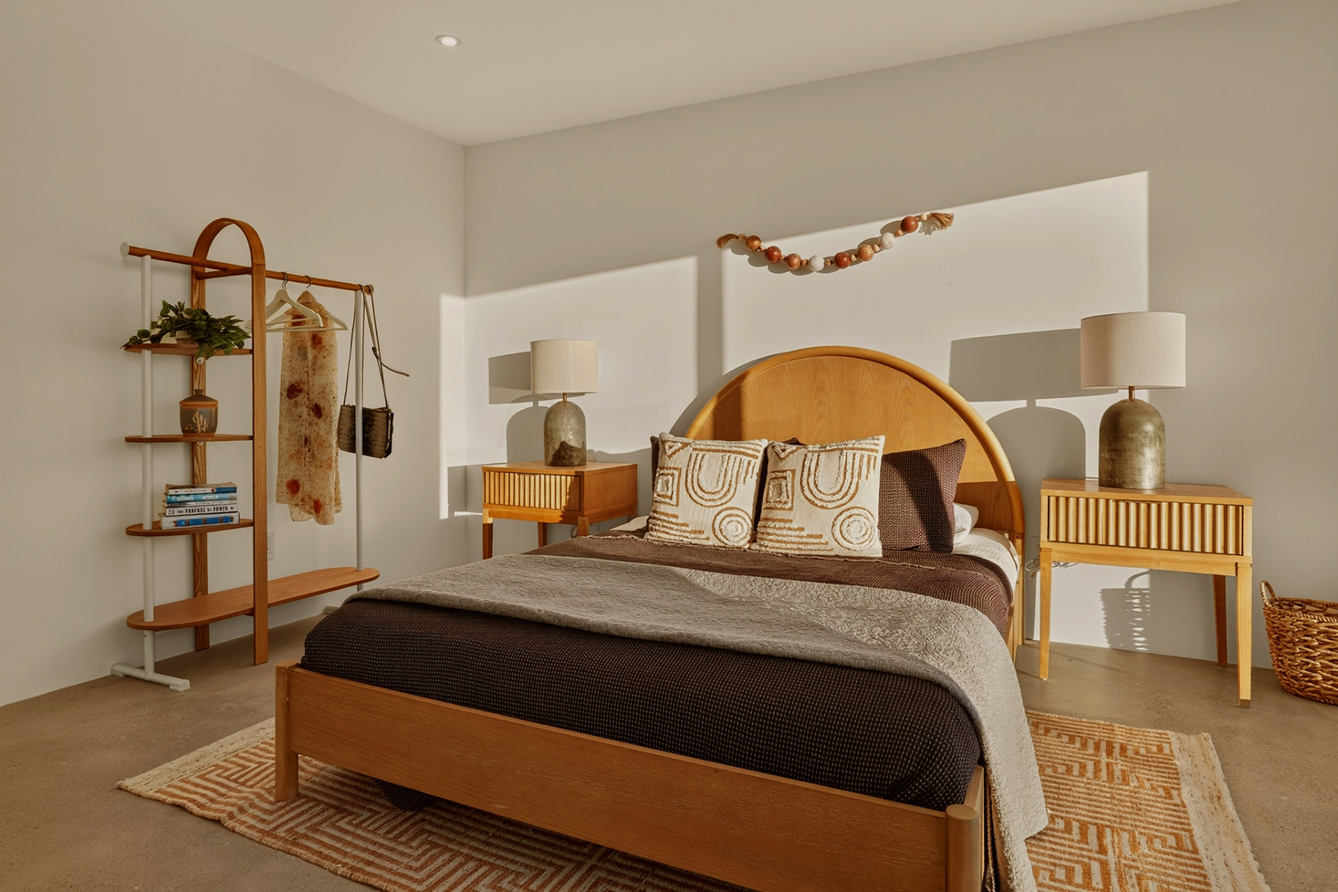 Bedroom with open shelving and morning light across the bed