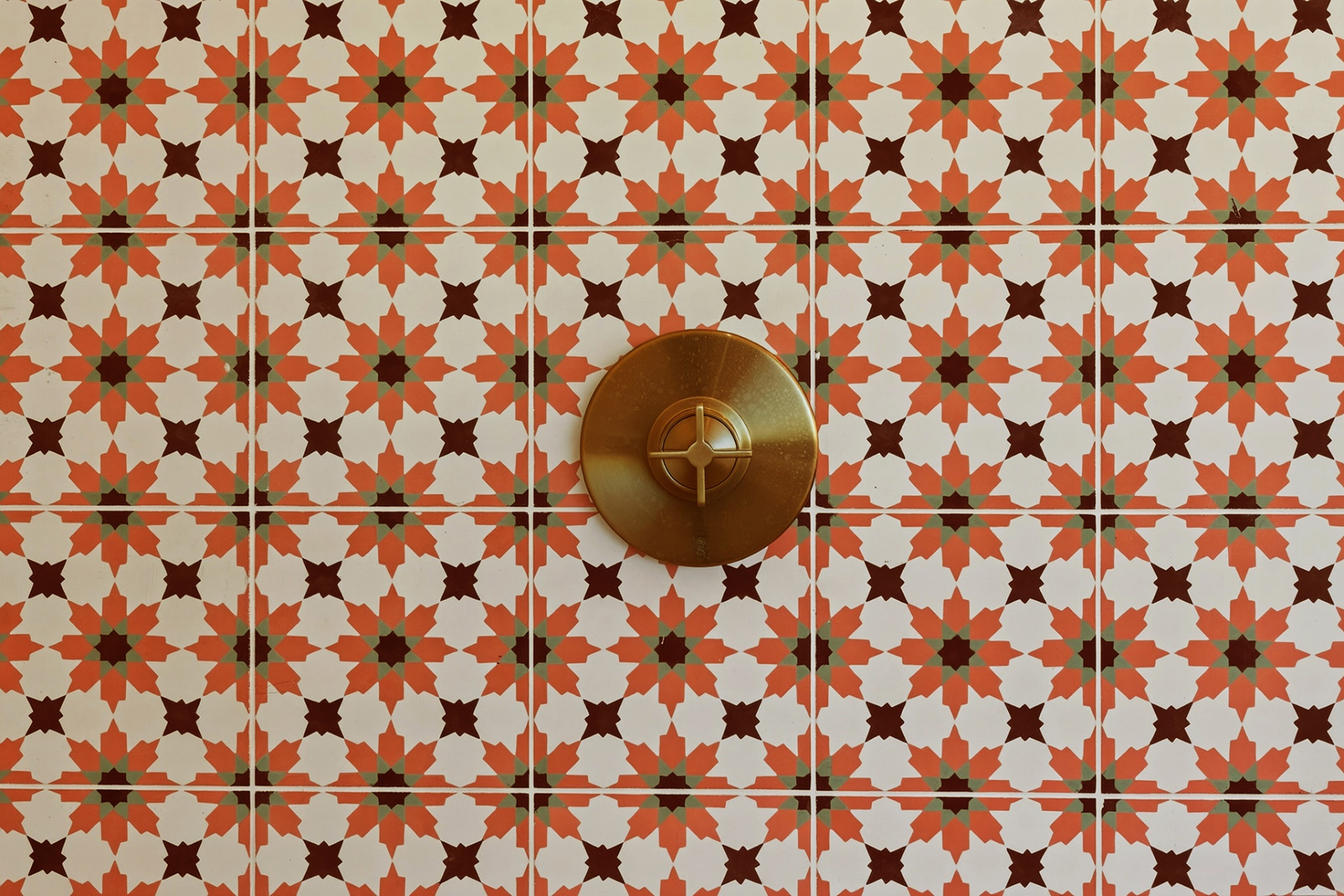 Close-up of patterned cement shower tile with brass fixture