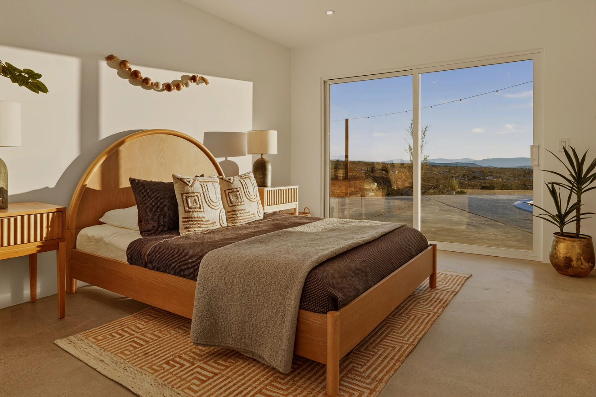 Bedroom with arched wood headboard and sliding glass door to the pool deck