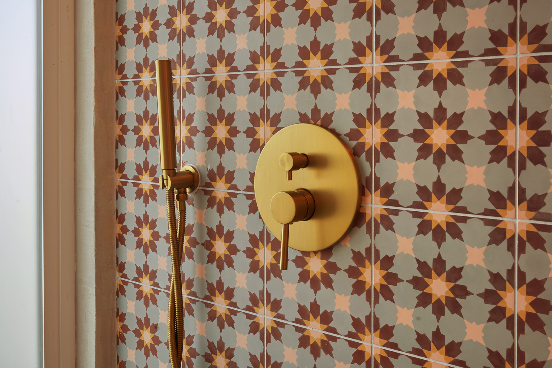 Close-up of brass shower fixture against patterned cement tile