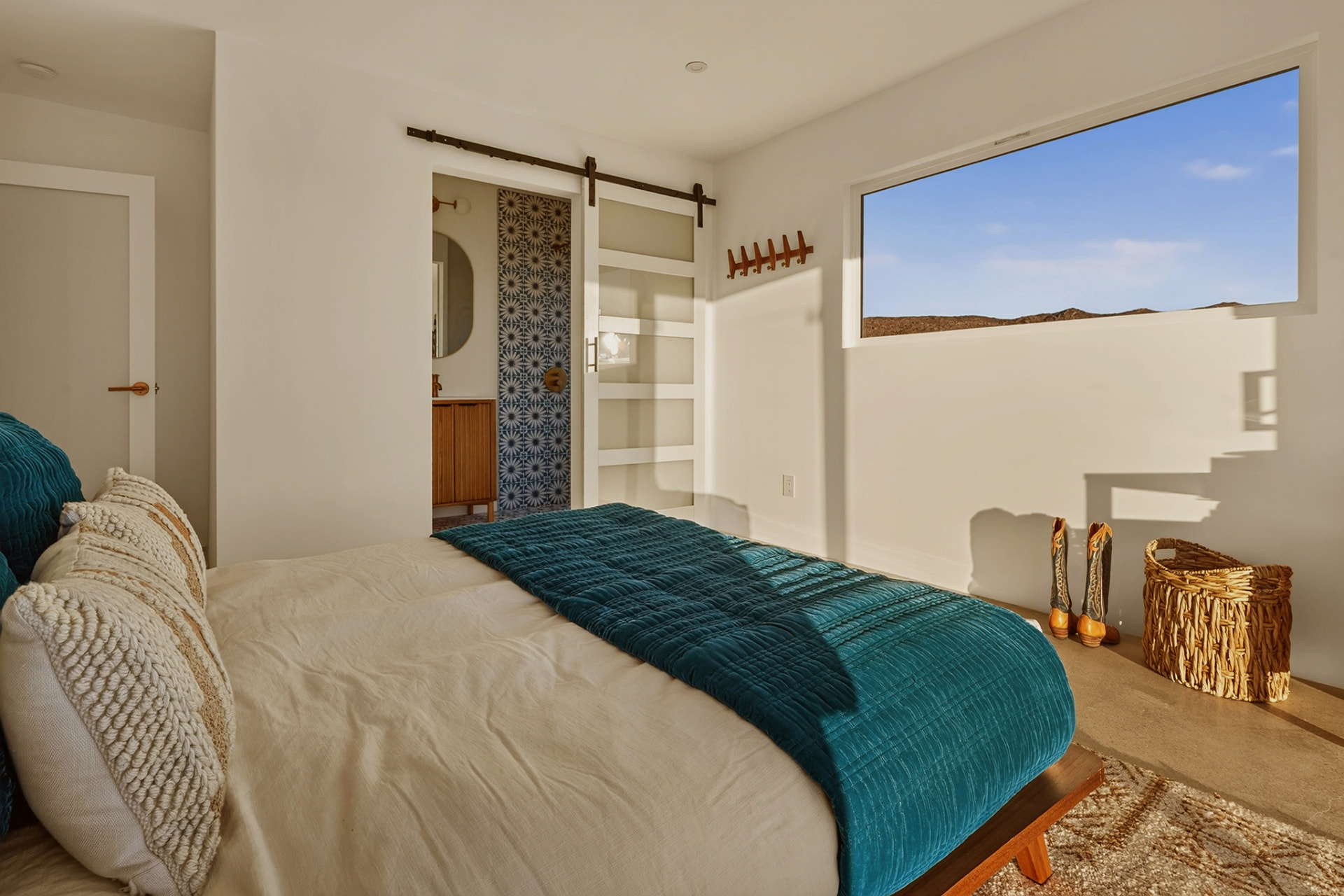 Bedroom with barn door to the bathroom and picture window over the desert hills