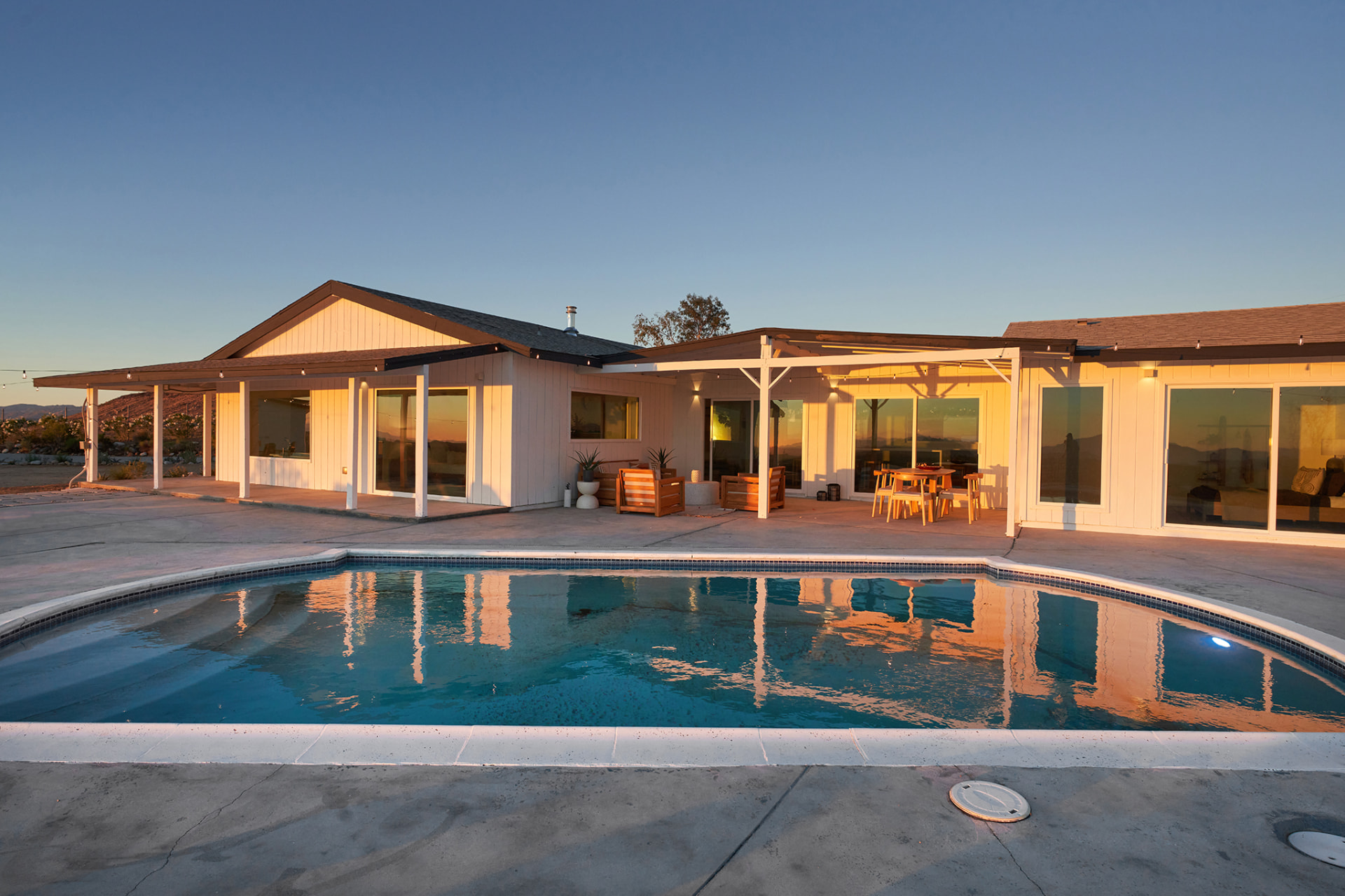 House and pool glowing at golden hour with patio dining