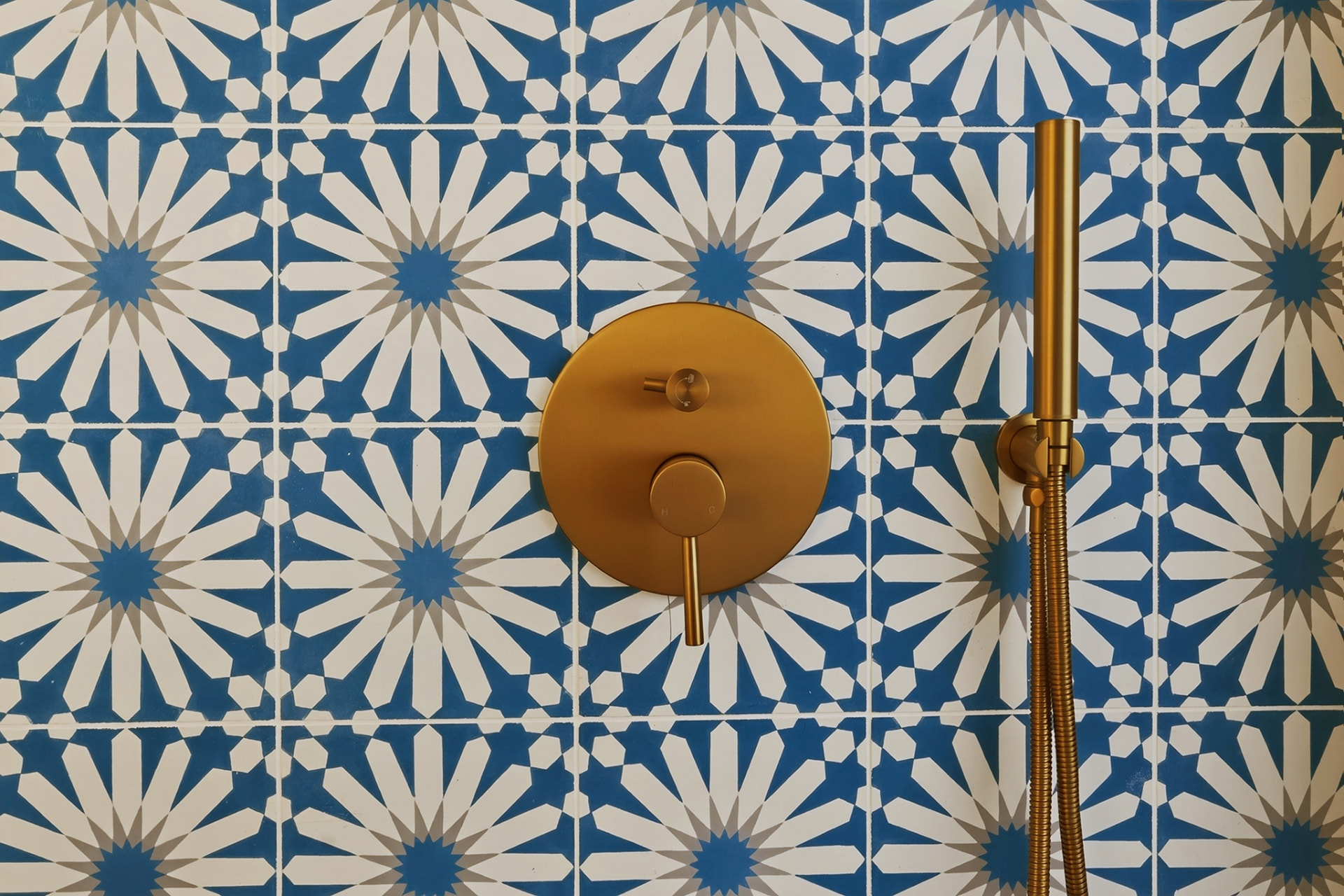 Close-up of brass shower valve against blue patterned cement tile